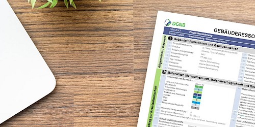 Ein Gebäuderessourcenpass liegt auf einem Holztisch neben einem Laptop