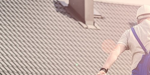 Eine Person springt vor einem Haus mit einem Bauplan