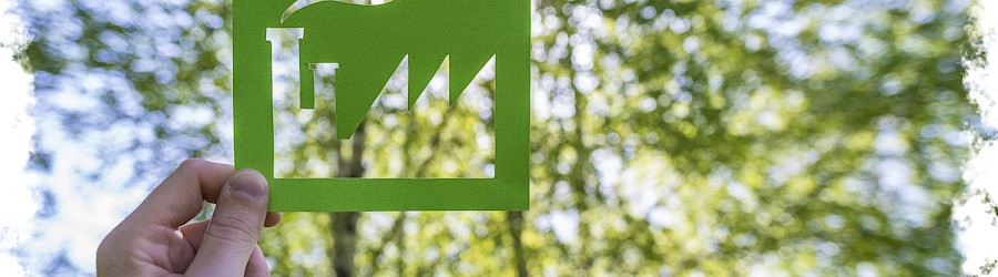 Grüner Zettel auf dem ein Industriegebäude ausgeschnitten ist um die grüne Industrie widerzuspiegeln