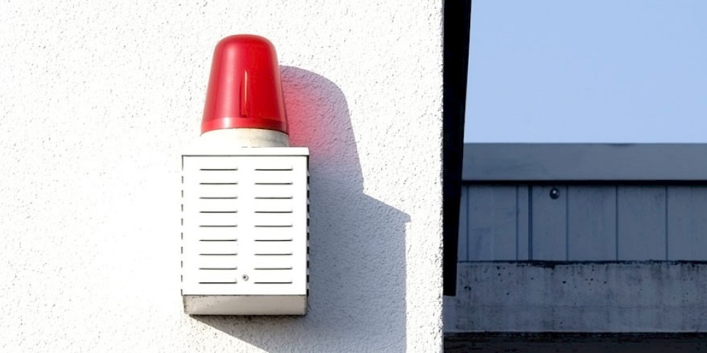 Signallampe hängend an einer weißen Wand und wirft einen Schatten