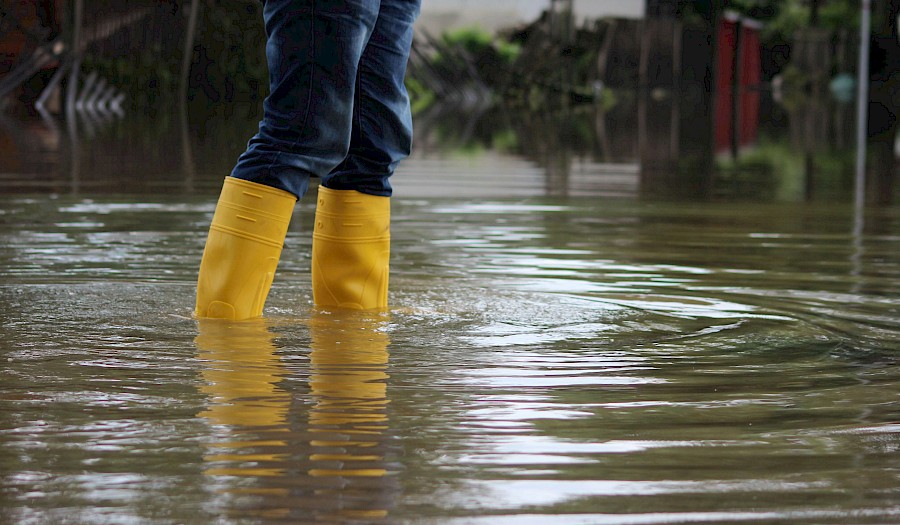 Person mit gelben Gummistiefeln steht im Wasser